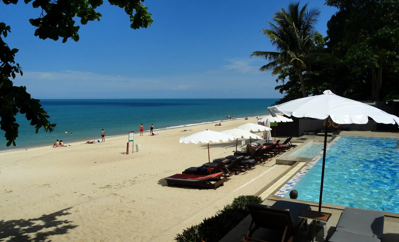 Sun loungers and a pool overlook the white sand and turquoise water of Lamai Beach, Koh Samui.