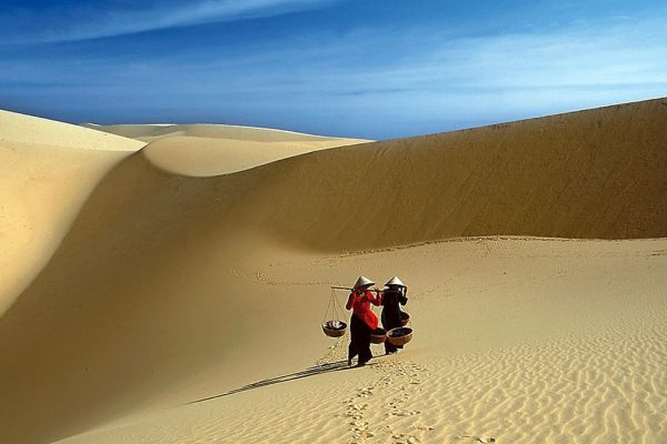 Red sand dunes rolling toward the coastline near Mui Ne